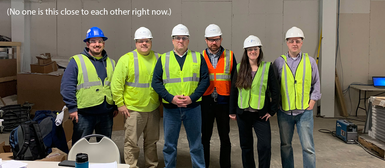 Service people wearing high visibility vests, hardhats and protective glasses.