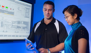A man and a woman looking at tablet in front of control system graphics, Automation and Control.