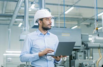 Technician in hardhat with laptop, asset reliability solutions, industrial reliability solutions, asset reliability services